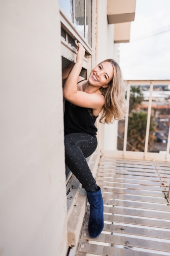 Jessica climbing through a window on a fire escape